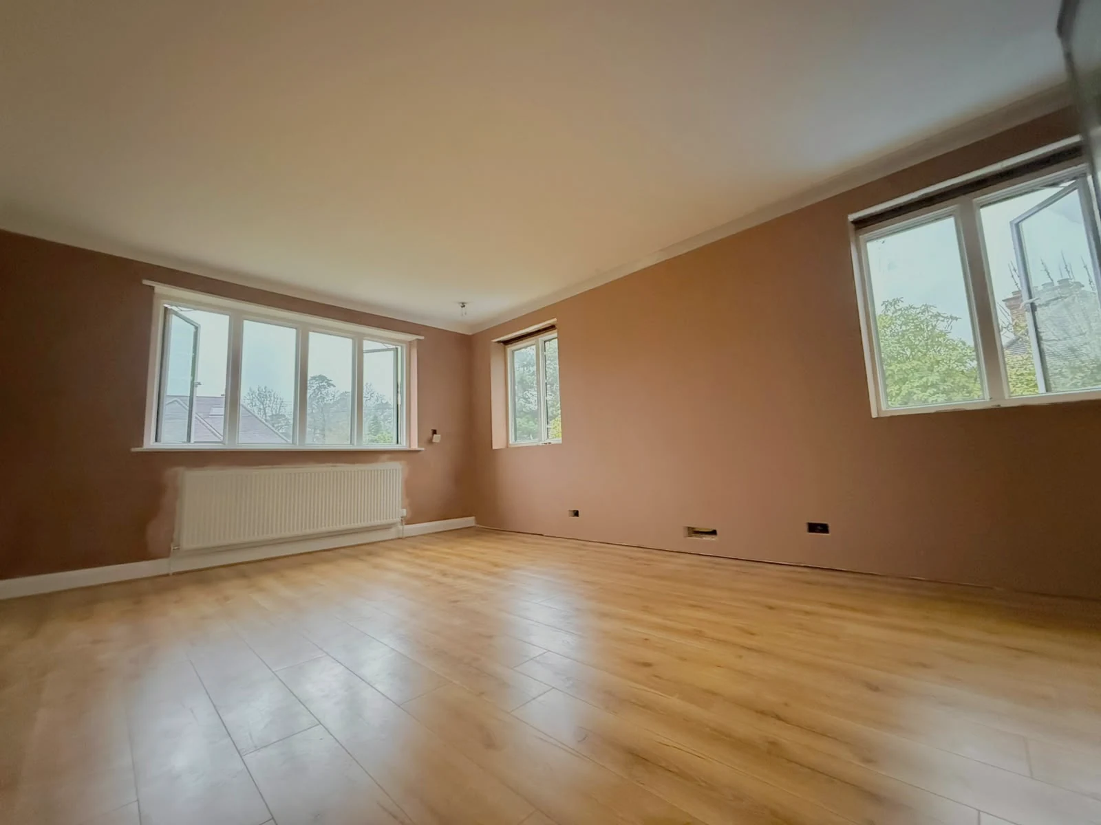 Freshly skimmed walls around three windows, with the floor and radiator retained